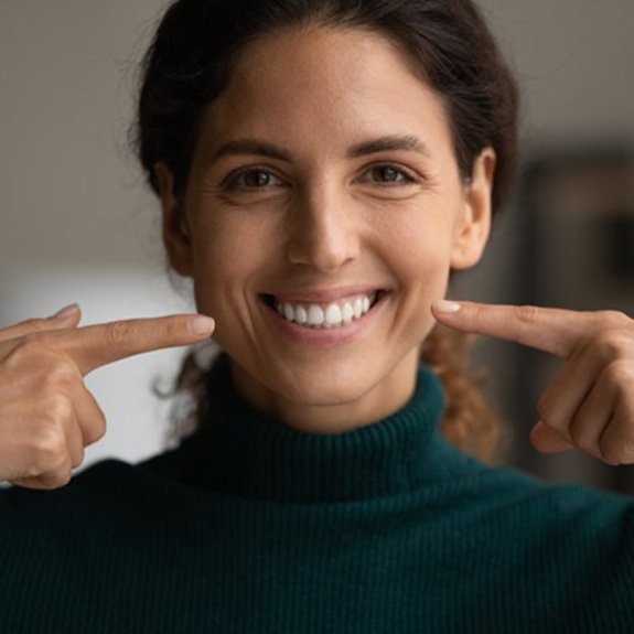 a woman smiling with straight teeth after undergoing Invisalign