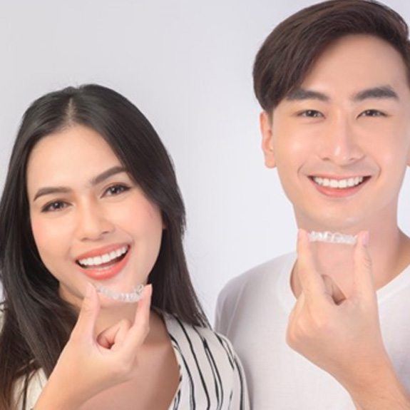 a couple holding their Invisalign aligners