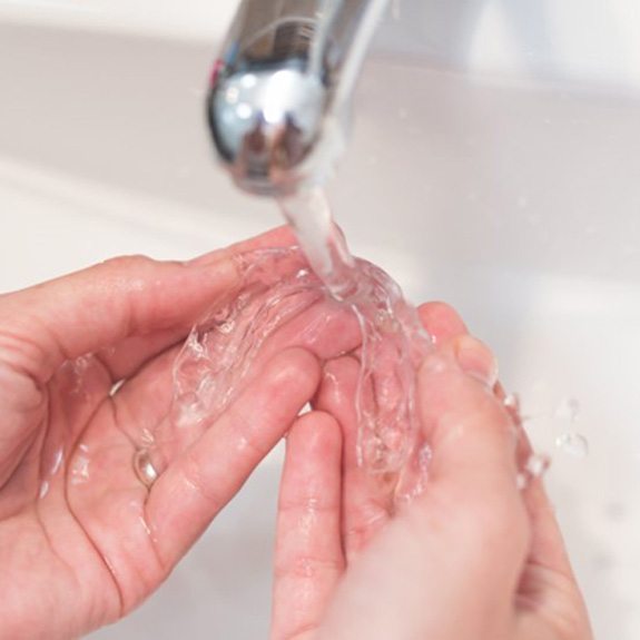 a person rinsing off Invisalign aligners