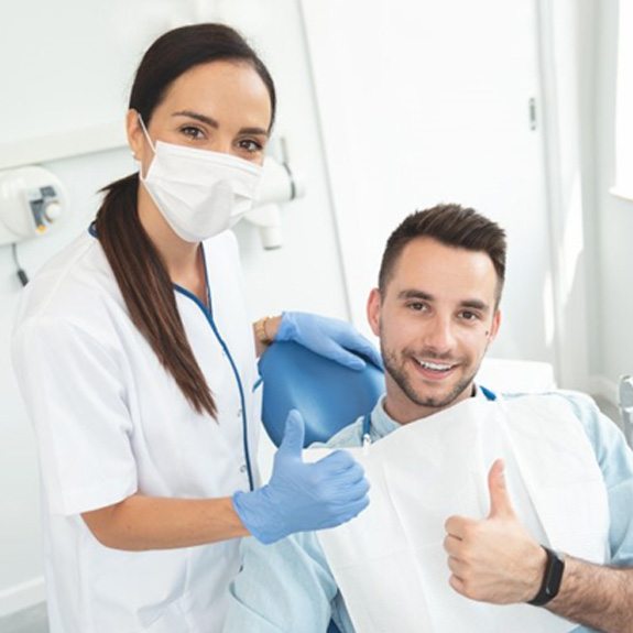 a dentist and patient giving thumbs up
    
        
