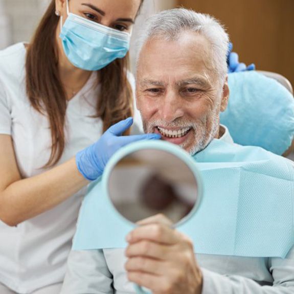 a dental patient checking his teeth with a mirror