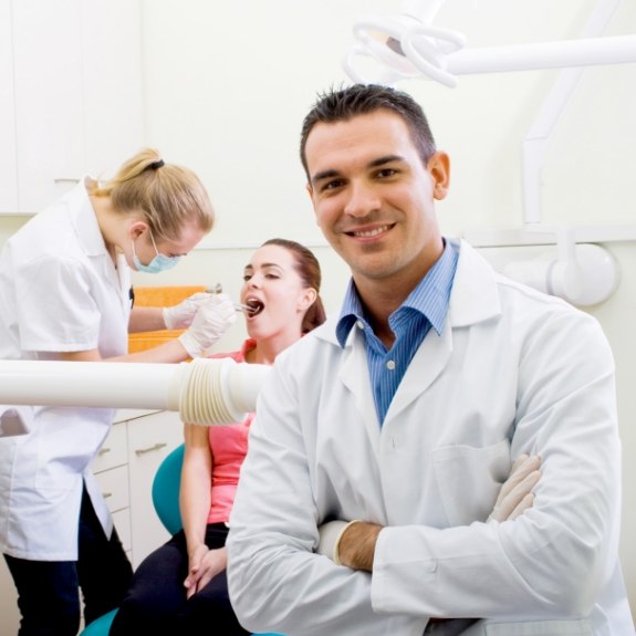 Dentist smiling as dental hygienist examines dental patient