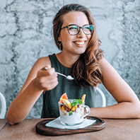 a woman with dental implants enjoying a healthy meal
