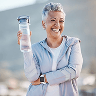 a mature woman with dental implants smiling during a hike