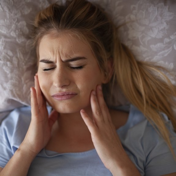 Woman with bruxism holding teeth in pain before using nightguard for teeth grinding