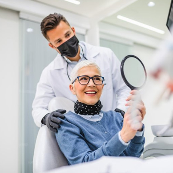 a patient checking her smile with a mirror