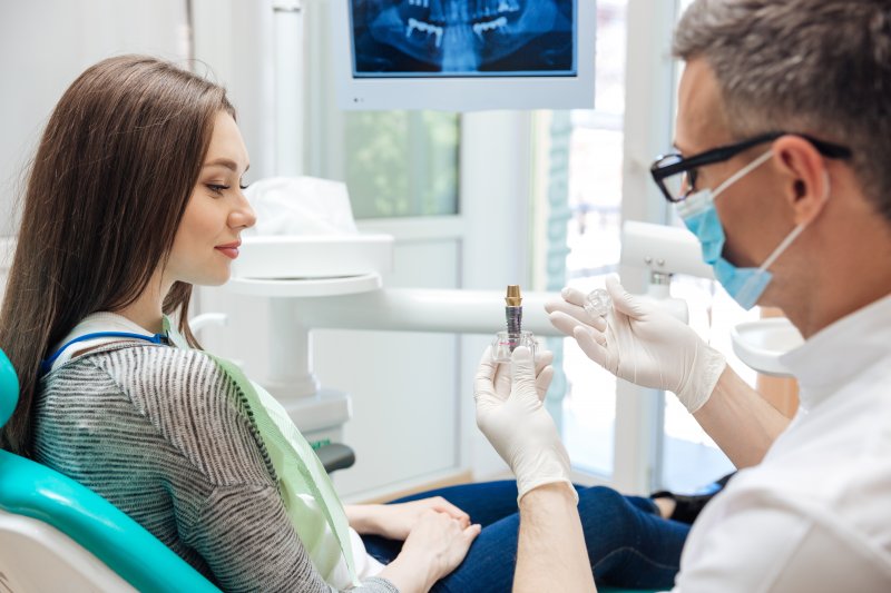 A dentist in Dublin holding a dental implant