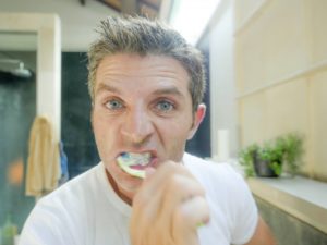 man brushing teeth too hard