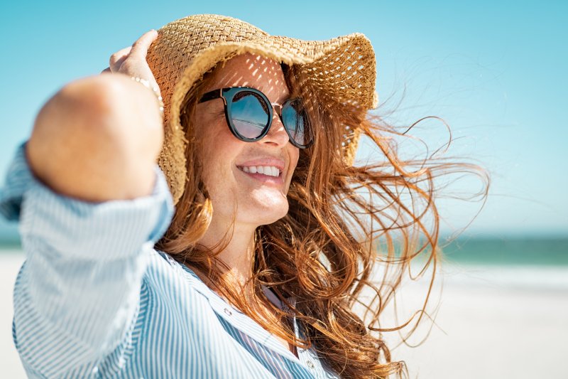 a woman smiling while visiting the beach