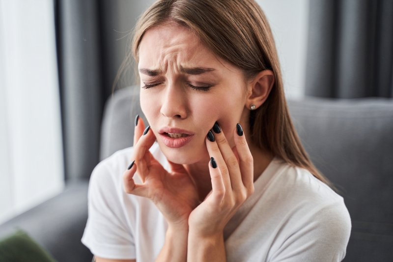 a woman touching her cheeks due to a dental emergency