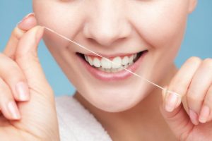 woman smiling while holding floss