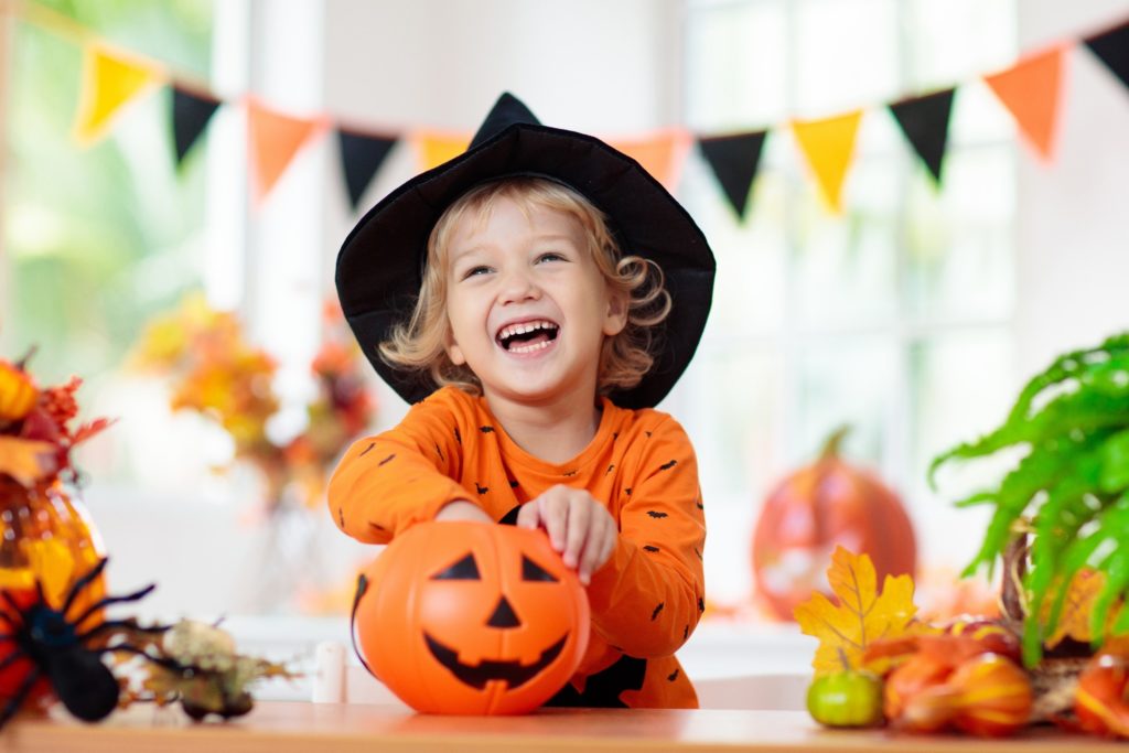 Child in witch hat eating Halloween candy