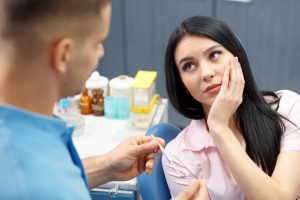 woman looks at dentist holding jaw