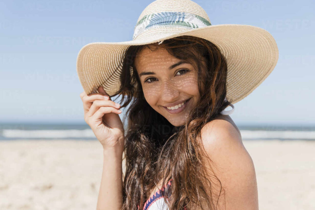 person who underwent cosmetic dental treatments smiling on beach