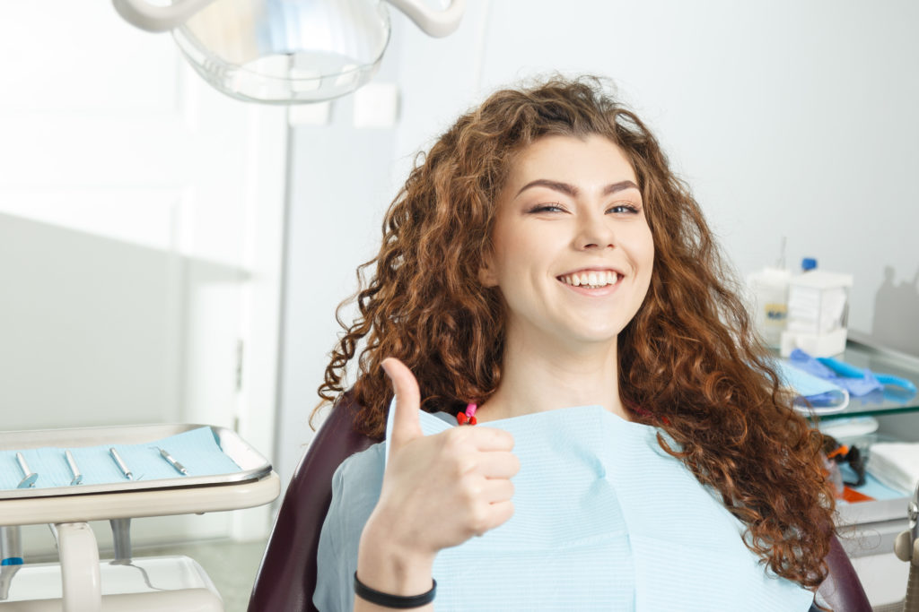 woman smiling while sitting in dentist chair for checkup