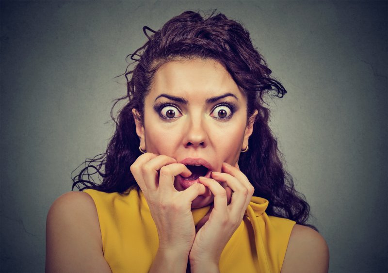 woman holding face in fear of receiving dental care